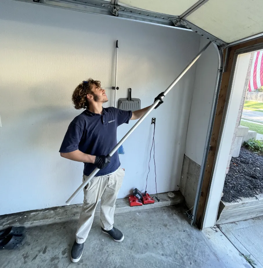A technician uses a long extension pole to apply HiveGuard Home Defense in Cincinnati, OH